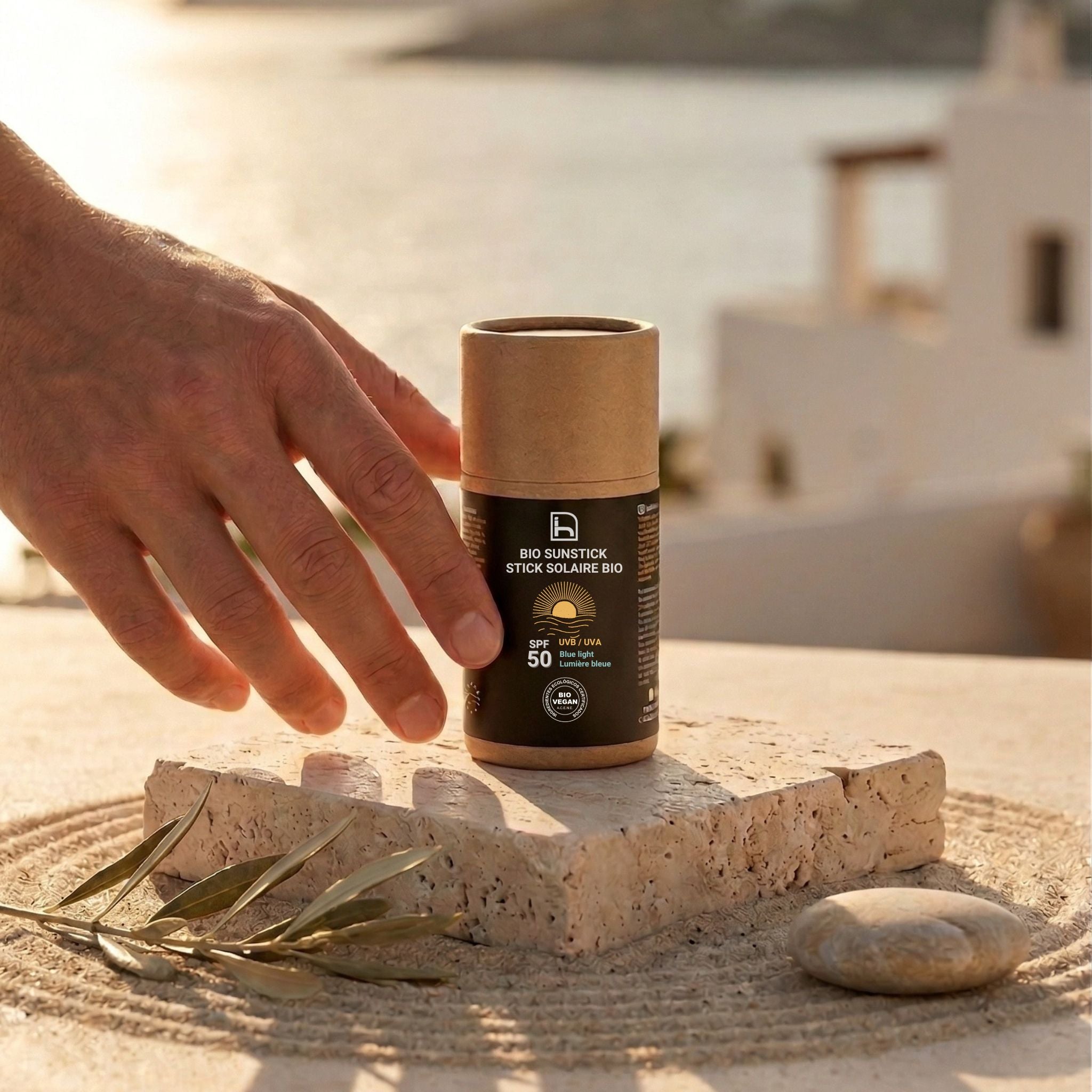 Bio Sunstick SPF50 de Homo Naturals en un entorno lifestyle mediterráneo premium, protector solar biodegradable para proteger la piel frente a la exposición solar.