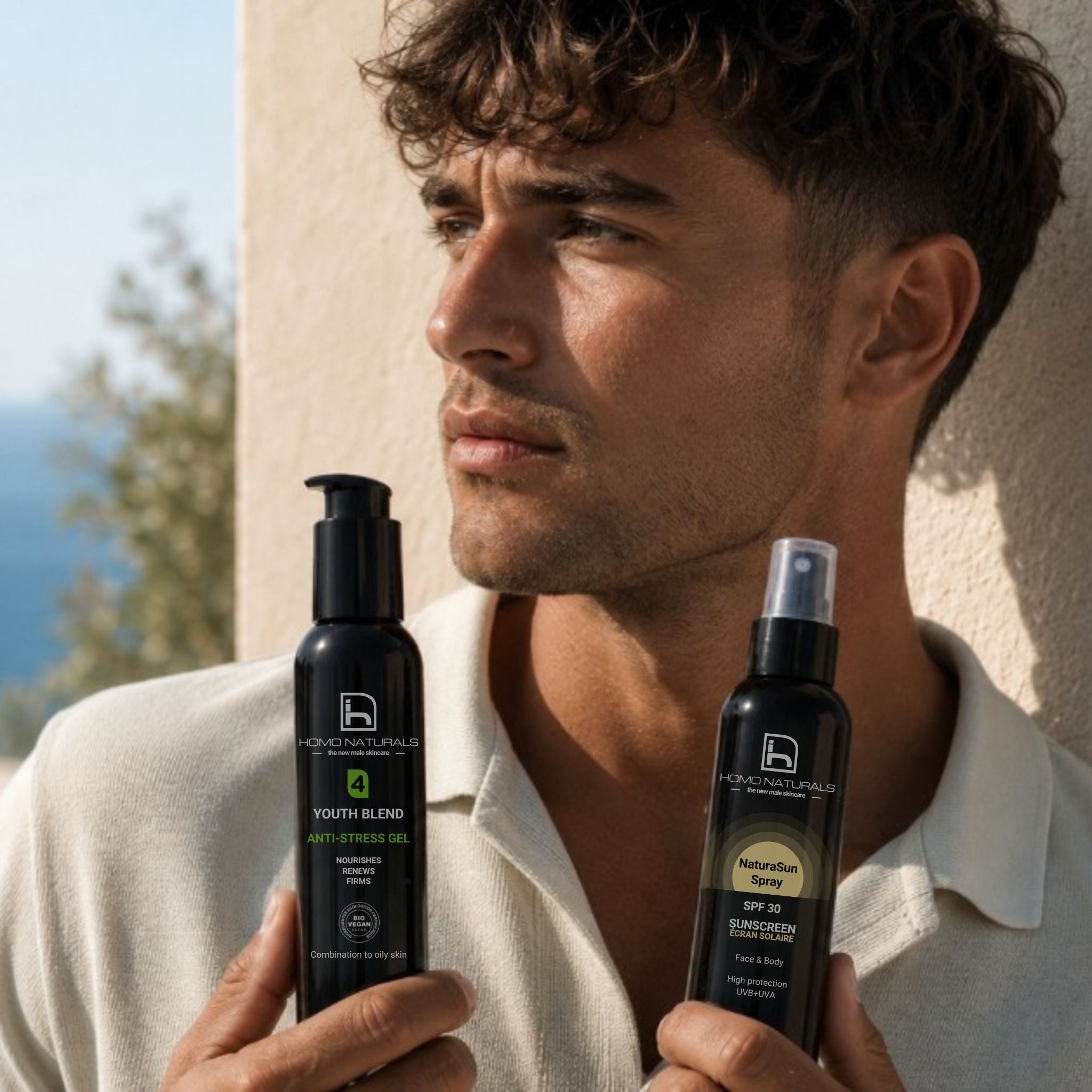 Imagen de un hombre sosteniendo el kit de cuidado facial de la marca Homo Naturals que incluye el gel o crema antiedad según el tipo de piel y el protector solar en spray. 